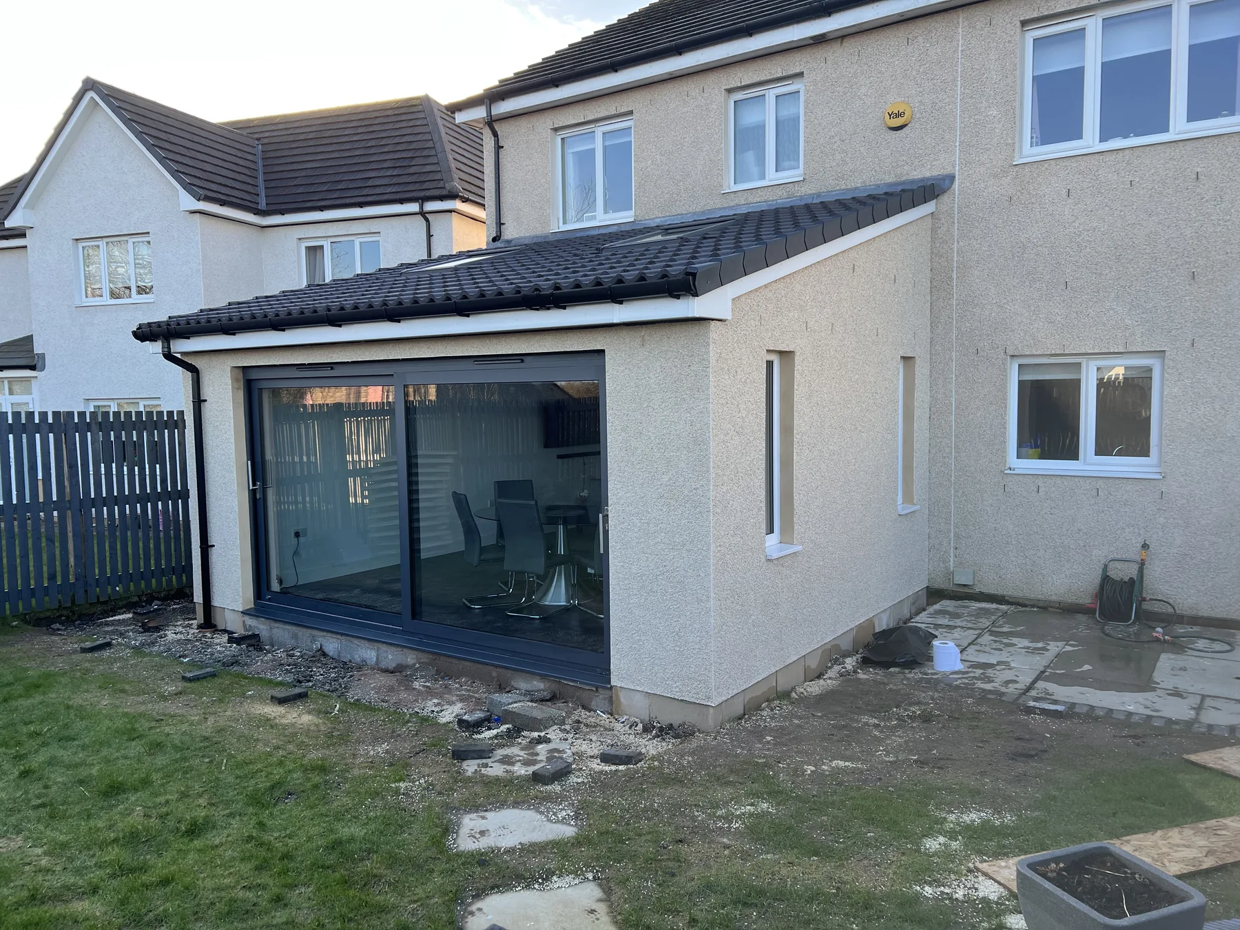 Rendered extension with wide glazed doors and unfinished ground outside