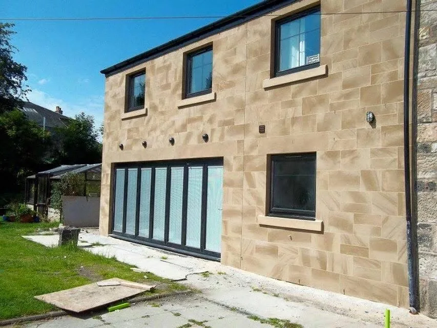 Stone finished house with dark framed windows and doors
